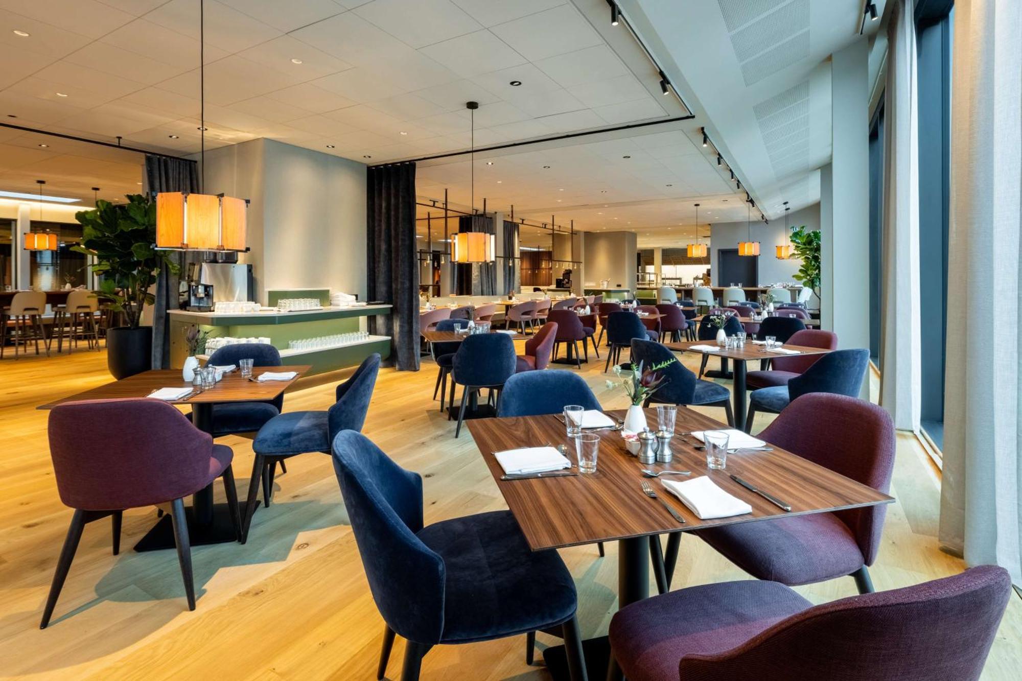 Nh Collection Copenhagen Hotel Bagian luar foto The photo showcases a modern restaurant interior with a spacious and elegant design. It features wooden flooring and a combination of light and dark furnishings. There are several tables set for dining, each with utensils and glasses. The chairs come